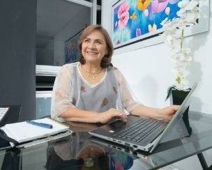 Profesional CLARITA MANRRIQUE de CYC SALUD S.A.S trabajando en su oficina frente al computador portátil, con actitud amable y experiencia, reflejando confianza y compromiso con el sector salud.