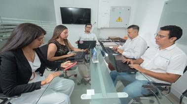 Profesional ANDREA RAMIREZ de CYC SALUD S.A.S atendiendo una llamada en su oficina, escribiendo en una libreta junto a un computador portátil, transmitiendo profesionalismo y cercanía.
